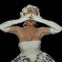 a woman in a white dress and white gloves is covering her eyes