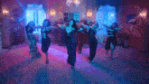 a group of women in black dresses are dancing in a room with blue lights