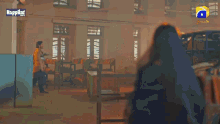 a woman is standing in a library with a happily tv logo on the bottom right