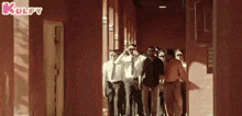 a group of people are walking down a hallway in a building .
