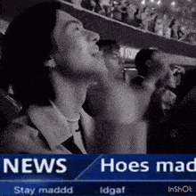 a man is standing in front of a crowd of people watching a news report .