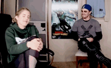 a man and a woman sit in front of a poster for arrow