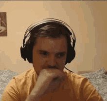 a man wearing headphones and a yellow shirt is sitting in front of a computer .