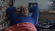 a man laying in bed with a gifrun.com watermark