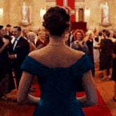a woman in a blue dress stands in a crowd of people