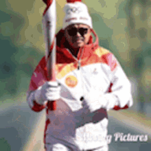 a man wearing a hat and sunglasses is running with a torch