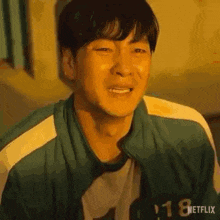 a man in a green jacket is crying and smiling in a painting .