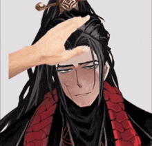 a hand is touching the head of a man with long black hair and a red scarf