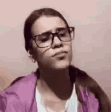 a girl wearing glasses and a purple jacket is making a face .