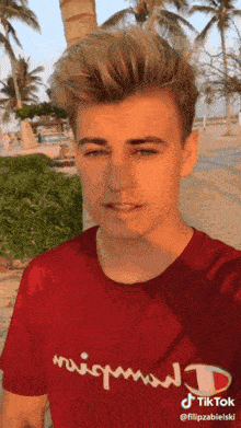 a young man wearing a red champion shirt is taking a selfie