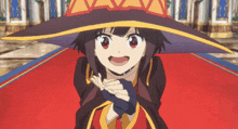 a girl in a witch hat is standing on a red carpet with her hands folded