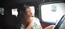 a woman is sitting in the driver 's seat of a car .