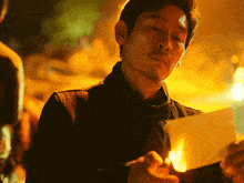 a man is holding a piece of paper that is burning in his hand
