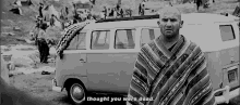 a man in a poncho is standing in front of a van and talking to it .