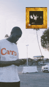 a man wearing a carrot t-shirt stands in front of a framed picture
