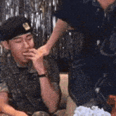 a man in a military uniform is sitting at a table with a cake .