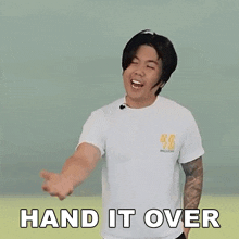 a man is wearing a white t-shirt and making a hand gesture with the words hand it over written on it .