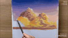 a person is painting a cloudy sky with white and orange paint