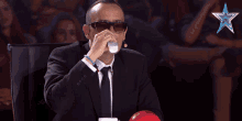 a man wearing sunglasses and a suit is sitting in front of a star