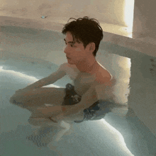 a shirtless man is sitting in a swimming pool with his legs crossed .