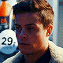 a close up of a man 's face with a bottle of soda in the background