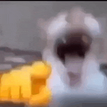 a blurry picture of a person with their mouth open and a yellow fist in the background .
