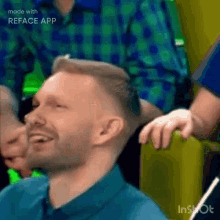 a man in a blue shirt is smiling and laughing in a video made with reface app