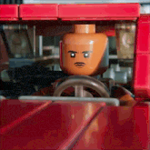 a lego man with a mustache is driving a red vehicle