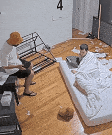 two men are sitting in a messy room with a poster on the wall that has the number 4 on it