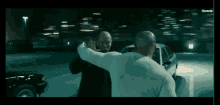 two men are fighting in a parking lot with the words filmmode on the bottom right
