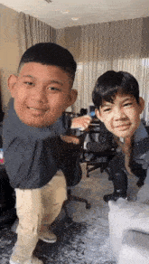 two young boys are standing next to each other in a room with their faces on a couch .