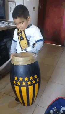 a young boy is playing a drum with a bandanna that says ba on it