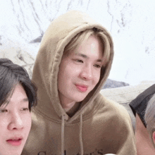 a man wearing a hoodie is making a funny face while sitting next to another man .