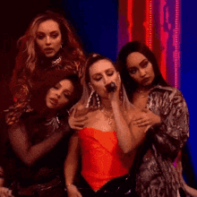 a group of women are standing next to each other on a stage and one of them is holding a microphone .