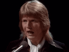a man singing into a microphone with a scarf around his neck