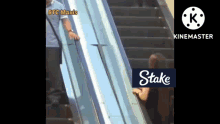 a woman is riding an escalator with a stake logo on it