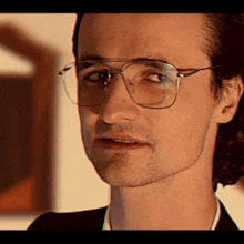 a close up of a man wearing glasses and a black suit
