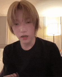 a young man with blonde hair wearing a black shirt
