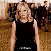 a woman in a black dress says " fuck me " in front of a crowd