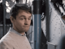a man in a white sweater is standing in front of a machine .