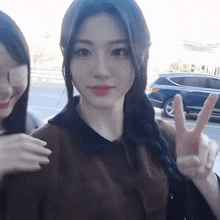 two girls are standing next to each other and one is giving the peace sign