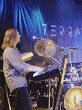 a man is playing a keyboard in front of a sign that says terra