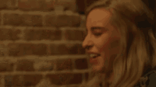 a blonde woman with red lipstick is making a funny face in front of a brick wall