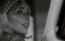 a black and white photo of a woman looking out the window