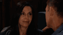 a man in a blue shirt looks at a woman in a black shirt