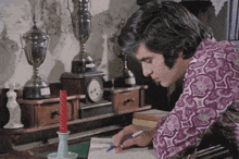 a man in a purple shirt writes on a piece of paper with a pen