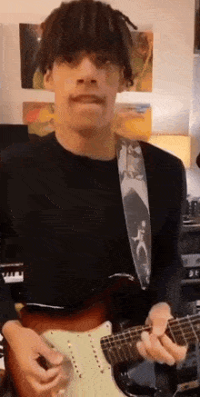 a young man is playing an electric guitar in a room with paintings on the wall .