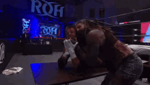 a wrestler is hugging another wrestler in front of a sign that says roh on it
