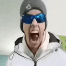 a man wearing sunglasses and a beanie is screaming .