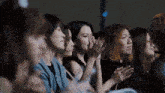 a group of women are sitting in a row clapping